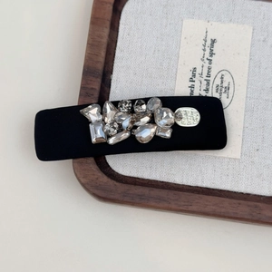 Close-up of black hair clip with sparkling rhinestones and crystals on a wooden tray