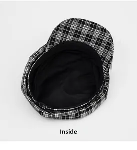 Detail view of the black and white plaid newsboy hat featuring inner lining and sweatband