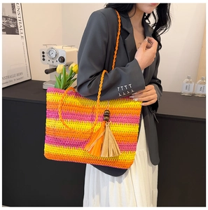 Detail shot of a large rainbow-striped straw tote bag with orange woven shoulder straps