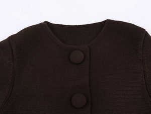Détail macro du cardigan en maille café foncé avec boutons recouverts et col rond