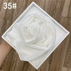 Détail d'une écharpe en mousseline blanche semi-transparente ornée de paillettes argentées