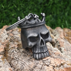 Macro detail of vintage skull with crown pendant on rustic wood texture and green background