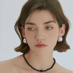 Irregular silver hoop earrings and black beaded necklace set worn by a fashion model