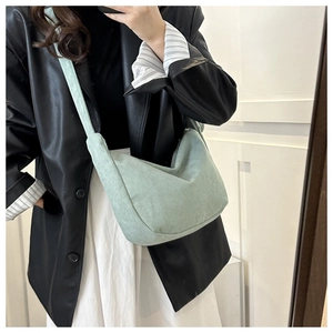 Sac bandoulière en velours côtelé vert menthe porté avec un blazer noir chic