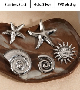 Detail view of silver stainless steel sea shell and starfish brooches on a ceramic tray