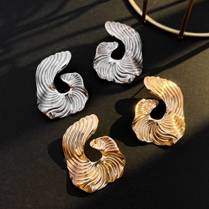 Close-up of irregular wave texture earrings in polished gold and silver metallic finishes