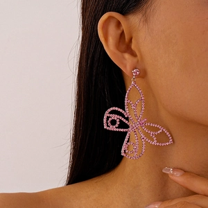 Close-up of sparkling pink rhinestone butterfly drop earrings worn on a female model