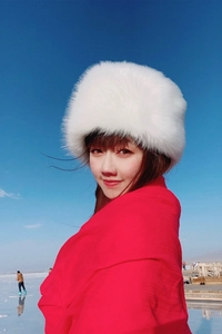 Detailed view of white faux fur winter hat and red scarf against a snowy lake background