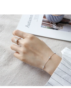 Detail view of S925 sterling silver four-prong solitaire ring with star charm bracelet