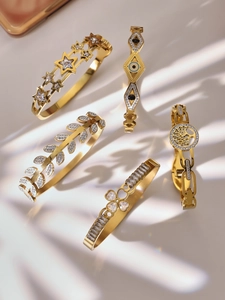 Detailed view of five 18k gold plated bracelets with zircon stars and floral motifs
