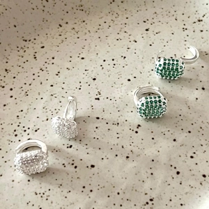 Close-up of 925 sterling silver hoop earrings with zircon emerald and white square pendants