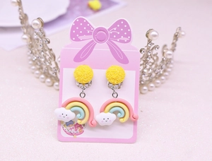 Close-up of cute resin rainbow and cloud clip-on earrings for kids on pink card
