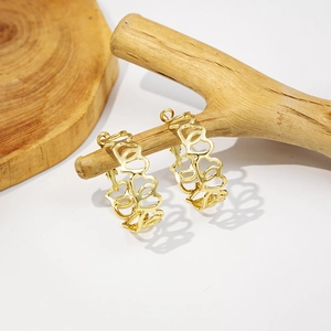 Detail of gold hollow heart hoop earrings hanging on natural wood branches display