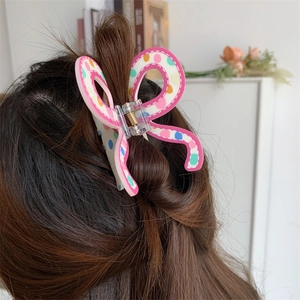 Pink and white butterfly hair claw with multi-colored polka dots worn on a half-up ponytail