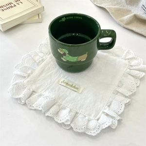Detailed view of square white lace coaster with delicate scalloped edges on a white table