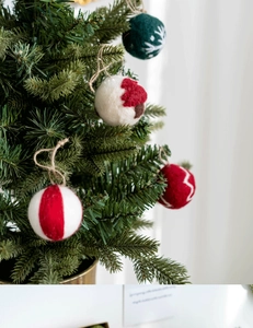 Detailed view of wool felt Christmas ornaments with snowflakes and trees hanging on a tree