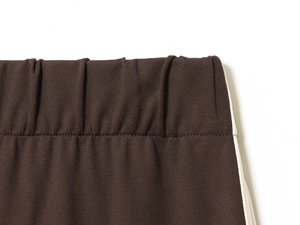 Detail of dark brown elastic waistband featuring white side stripes and premium knit texture