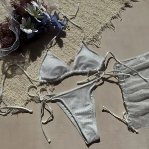 Détail d'un ensemble bikini 3 pièces en résille blanche avec jupe de plage assortie