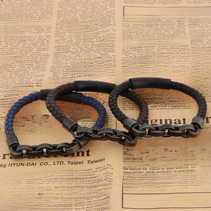Detail of woven brown and blue leather bracelets with vintage metal chains on old newspaper