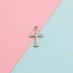 Vue détaillée d'un pendentif croix en acier inoxydable sur fond rose et bleu clair