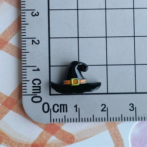 Mini resin black wizard hat charm with orange band measured on a centimeter scale