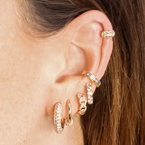 Macro shot of gold-plated hoop earrings and ear cuffs with micro-pave zircons for ear stacking