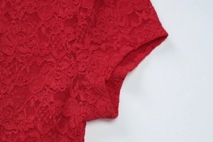 Détail de la manche en dentelle rouge avec broderie élégante et coutures de précision