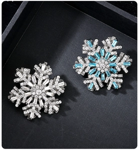 Detailed view of silver snowflake brooches with clear and blue crystals on black background
