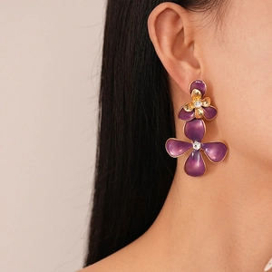 Detailed view of vintage purple enamel flower earrings with crystal center on model