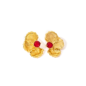 Detail of vintage gold flower stud earrings with a central red stone inlay and textured petals