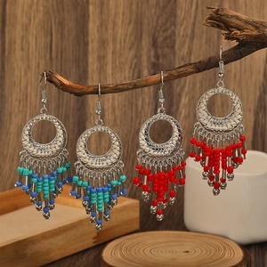 Bohemian style beaded tassel earrings with vintage silver metal pendants on wood branch