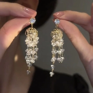 Gros plan de boucles d'oreilles pendantes dorées avec strass et perles de cristal