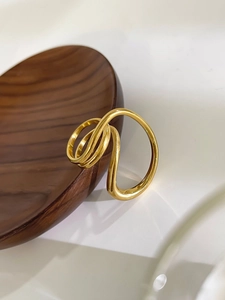 Close-up of 18K gold multi-layered geometric ring on a dark wooden display plate
