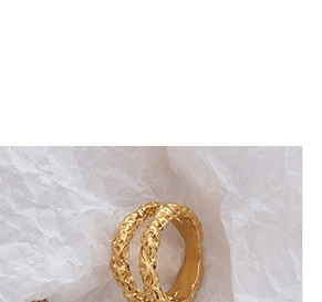 Macro shot of gold-plated double-layer ring with textured lava ripples on white paper