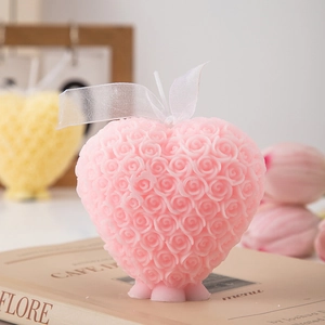 Detail of pink heart-shaped rose scented candle on vintage book for home decor