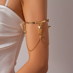 Detailed view of a gold metal arm cuff with delicate butterfly tassel chains and pendants