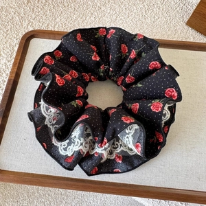Détail d'un chouchou en dentelle fleurie avec roses rouges et pois blancs sur bois