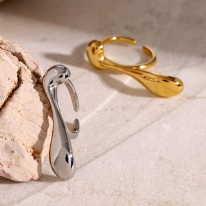 Abstract teardrop irregular curve open rings in gold and silver on stone surface
