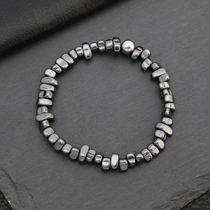 Macro detail of irregular hematite beaded bracelet with a grey accent stone on stone base