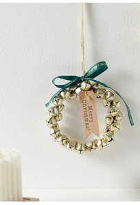 Close-up of golden Christmas bells wreath with green ribbon and Merry Christmas tag