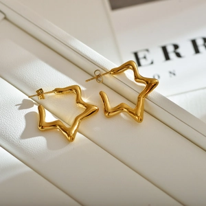 Minimalist gold star stud earrings in polished stainless steel on a white textured stand