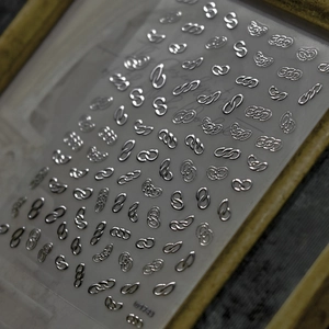 Detailed macro view of 3D embossed silver metal chain patterns for luxury nail art stickers
