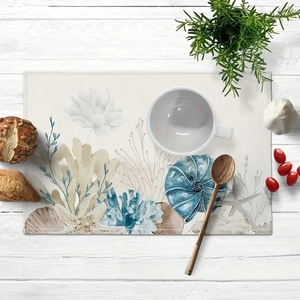 Detail of seashell beach placemat with watercolor coral and flower patterns on wood table