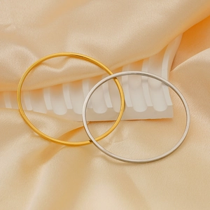 Close-up of minimalist gold and silver titanium steel bangles on silk fabric