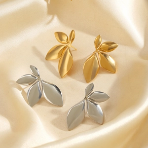 Minimalist gold and silver leaf earrings displayed on beige silk fabric background