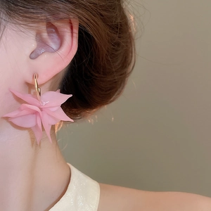Detail of model wearing pink acrylic flower petal earrings with golden hoop accents