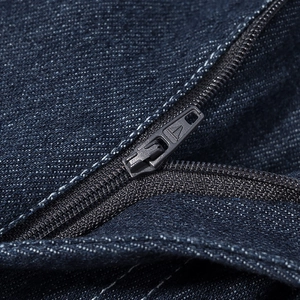 Gros plan du tissu denim bleu foncé avec fermeture éclair en métal et coutures doubles blanches