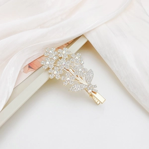 Close-up of golden flower hair clip with sparkling rhinestones on soft white fabric