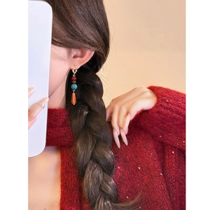 Détail de boucles d'oreilles bohèmes avec perles turquoise et corail portées par le mannequin