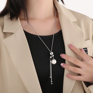 Dettaglio di una collana con nappine e perle argento indossata con un blazer elegante